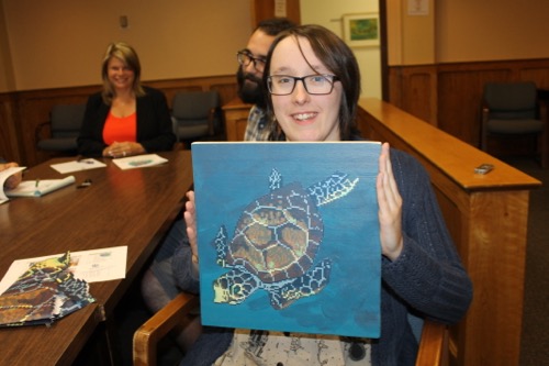 Illustrator Samantha Neukirch with a sample of the images she'll create for a mural to adorn a wall inside the downtown playground. Photo: Denise Civiletti