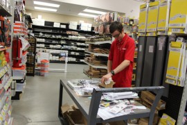 Spencer places security tags on items before hanging them in the aisle. Photo: Katie Blasl