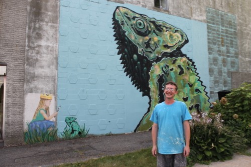 Mural artist Drew Kane with his "Chameleon" on the wall of the East Main Street building next to First Congregational Church. 