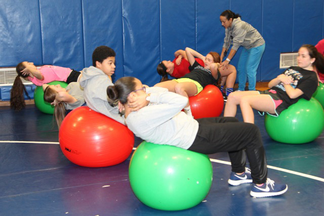 Riverhead High Schoo PE teacher Maria Dounelis coaches the students in the proper way to do Swiss Ball Ab Crunches.